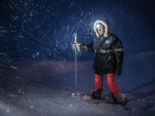 Scientist in snow with headlamp and probe