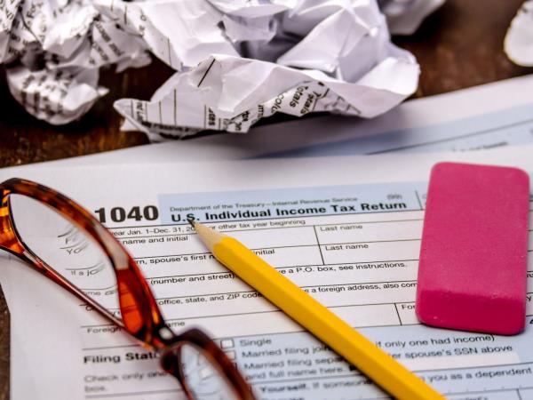 Tax form 1040 with crumpled up forms, glasses, pink eraser and pencil