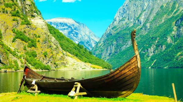 A lush green fjord in Norway with a wooden longship.